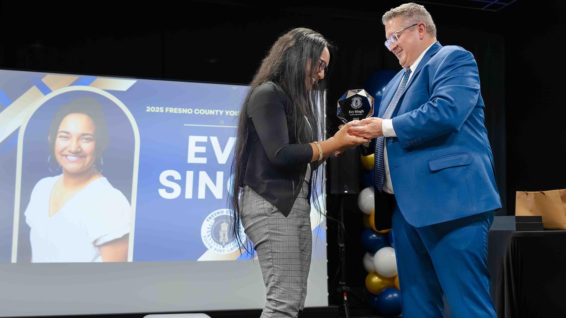 The new Fresno County Youth Poet Laureate is accepting her award from the FCSS Director of Arts Education.