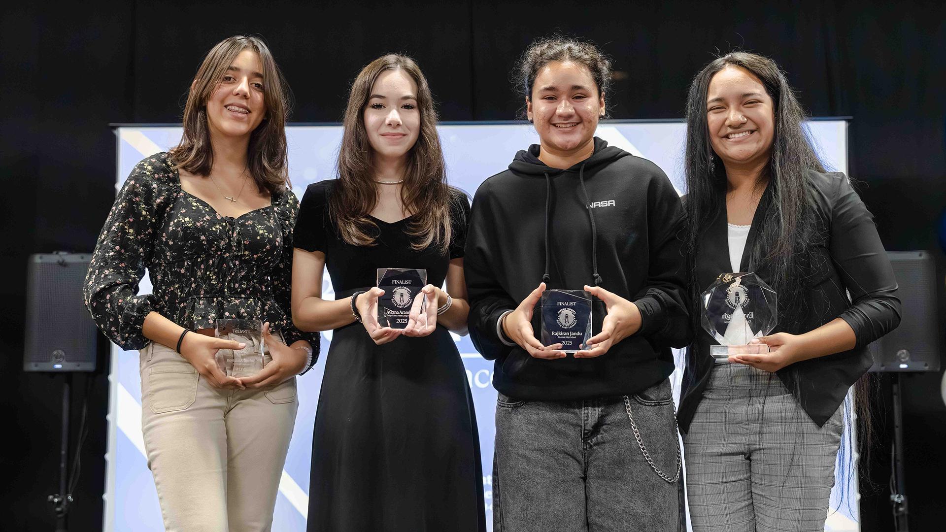 The four smiling finalists are standing, holding their awards.