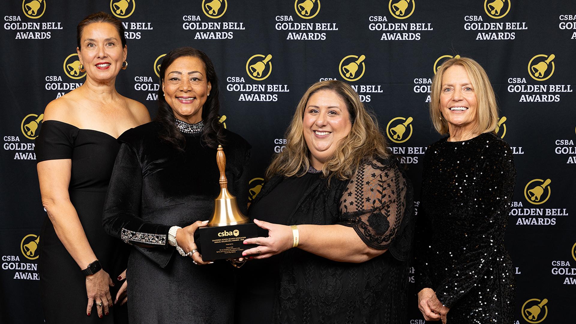 Awardees and VIPs are standing together, smiling, after accepting the Golden Bell award.