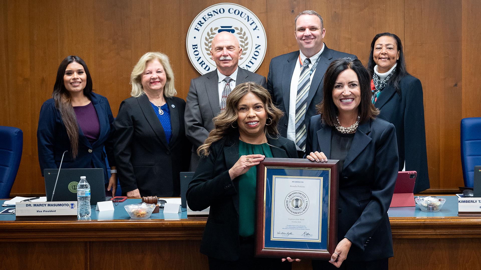 The smiling honoree is holding her plaque surrounded by the Fresno County Board of Education and the Fresno County Superintendent of Schools.