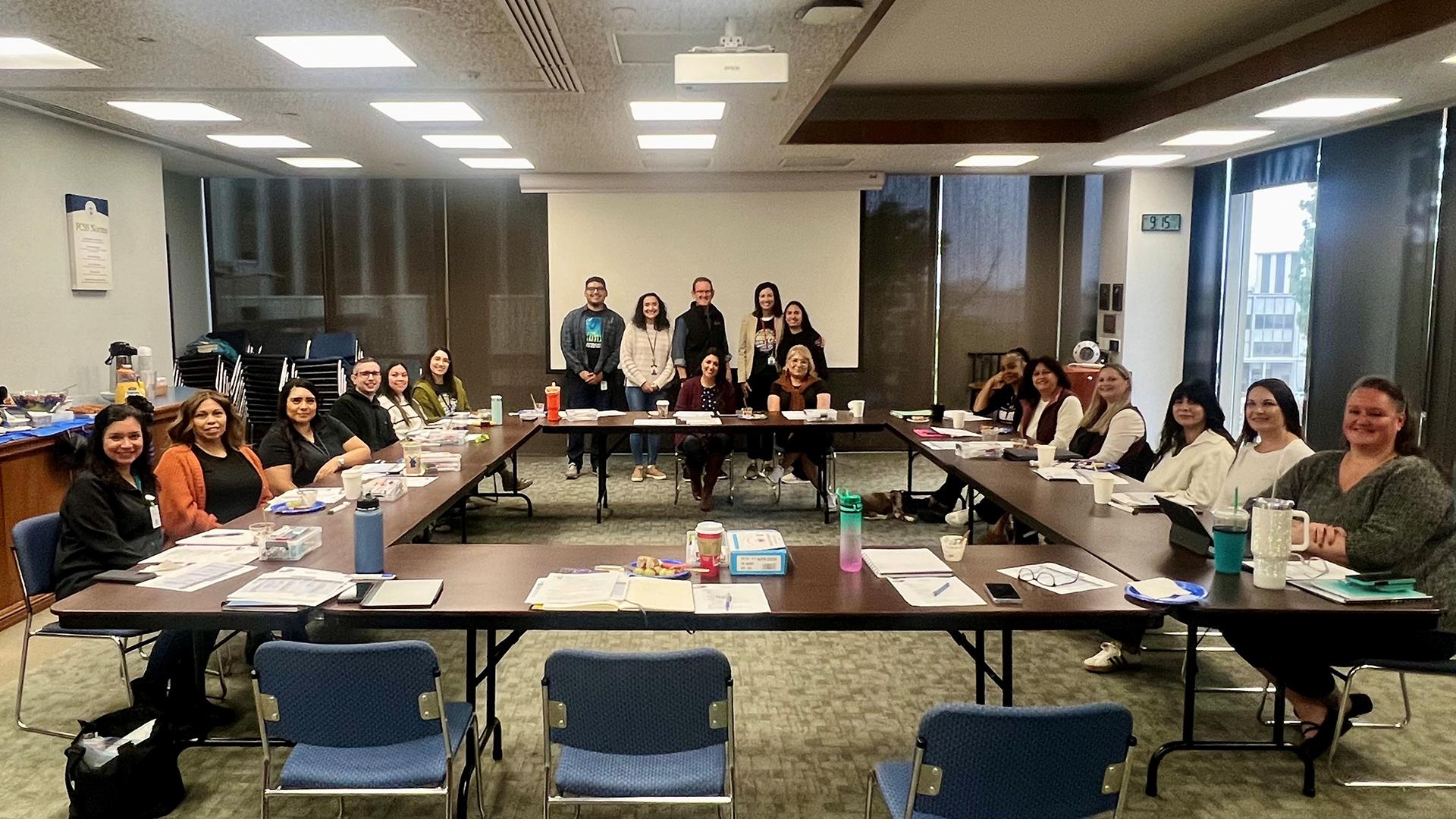 Attendees are seated at a table, smiling.