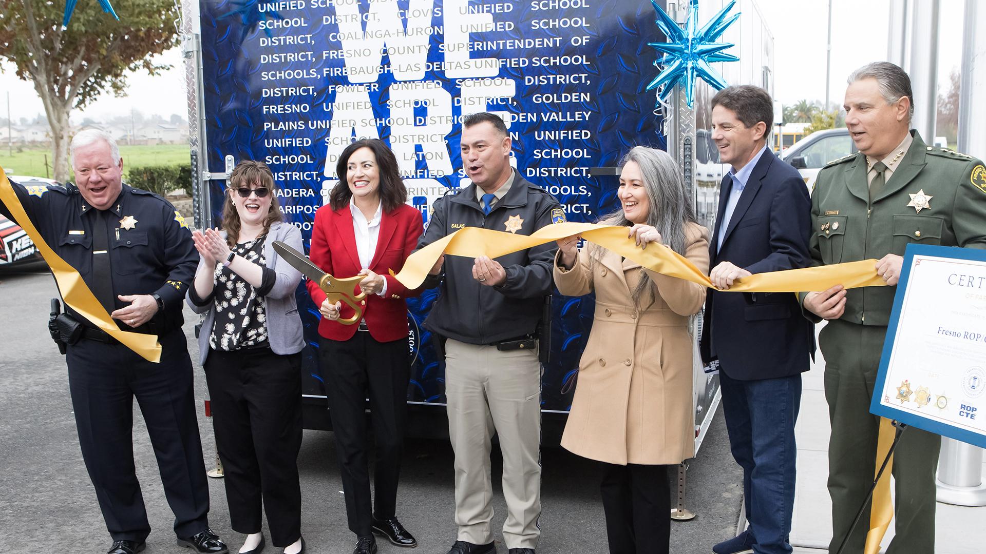 A line of dignitaries cuts the ribbon to the new Dispatch Trailer.