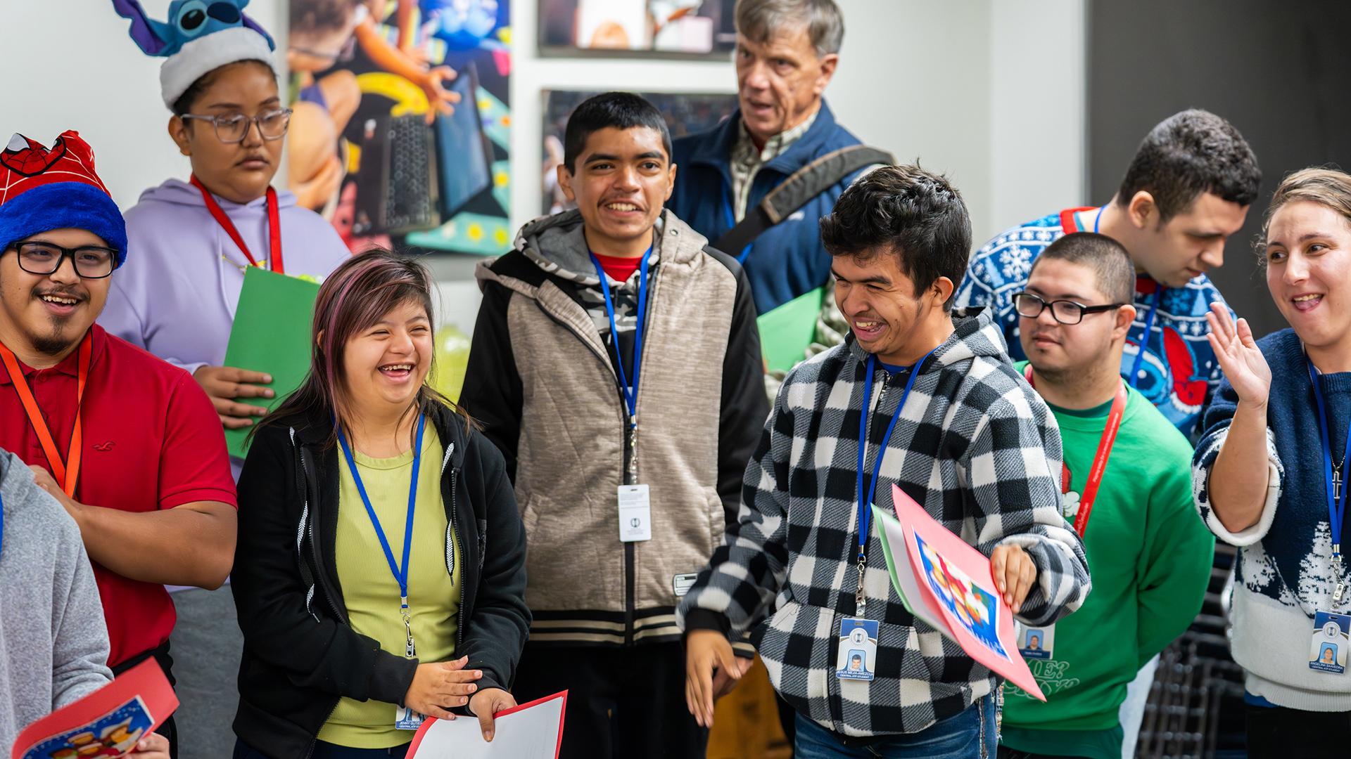 Students are standing together, happy and smiling, as they sing Christmas carols.