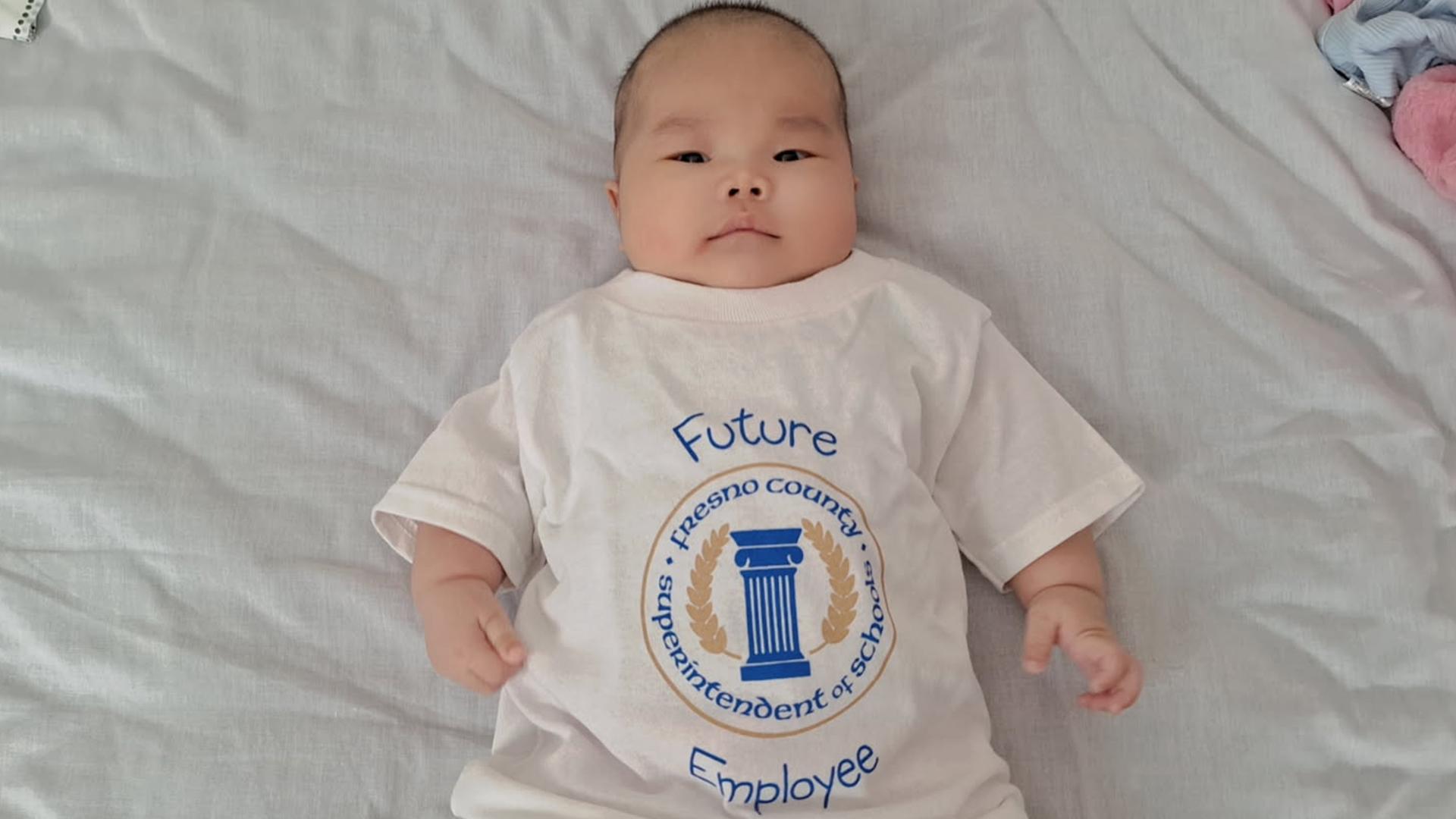 The baby is laying on a bedspread.