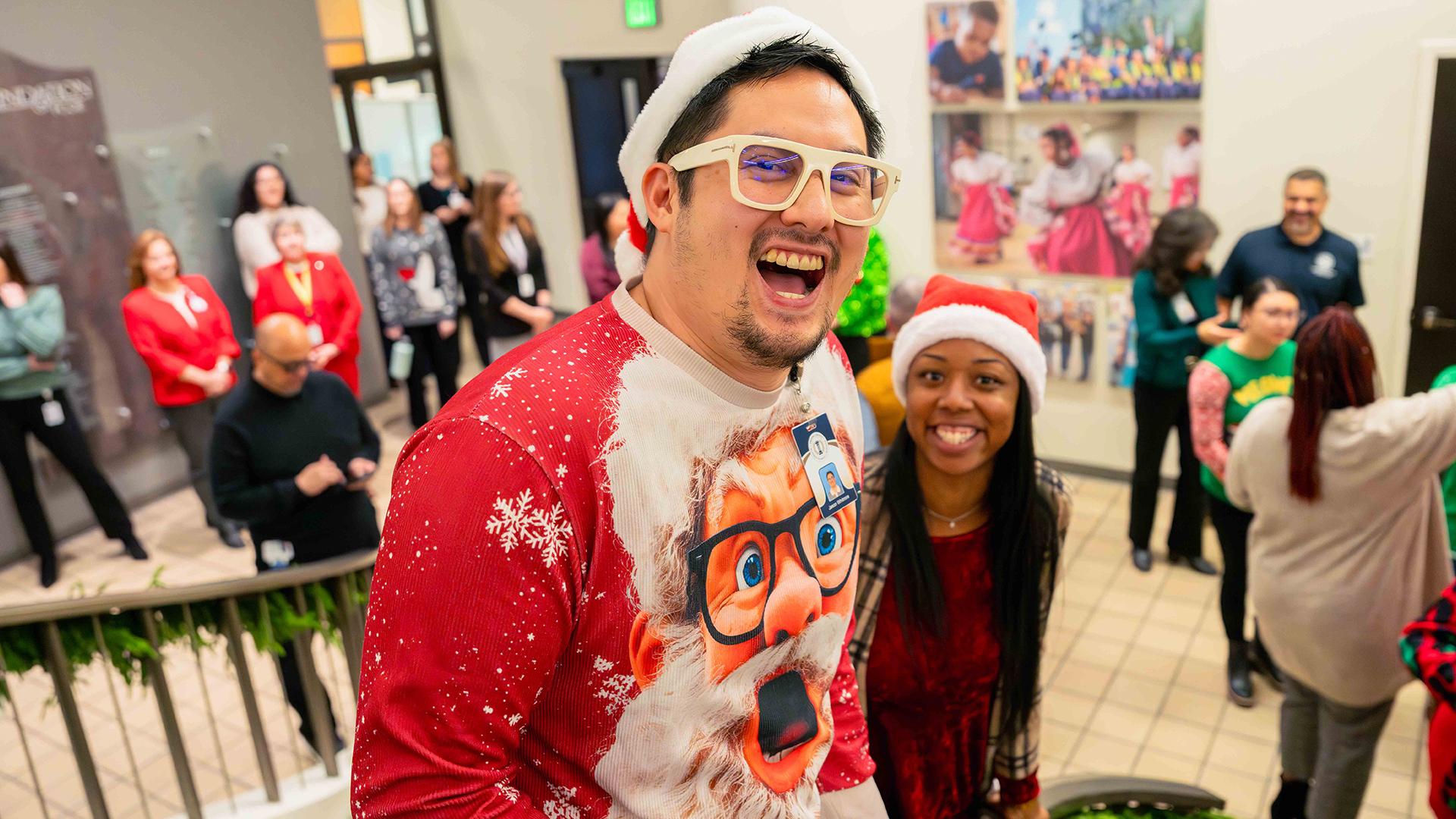 Two staff members wearing Santa hats smile at the camera.