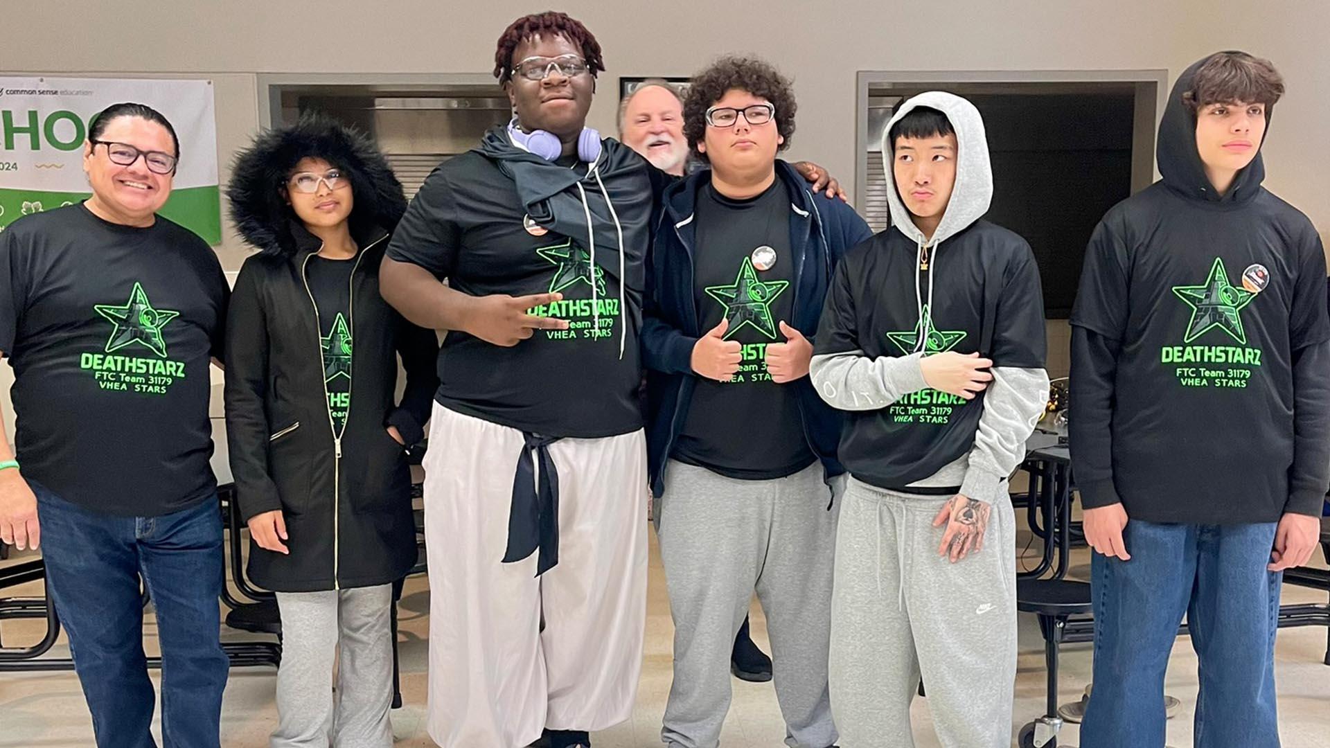 The VHEA robotics team stands in a line and smiles.