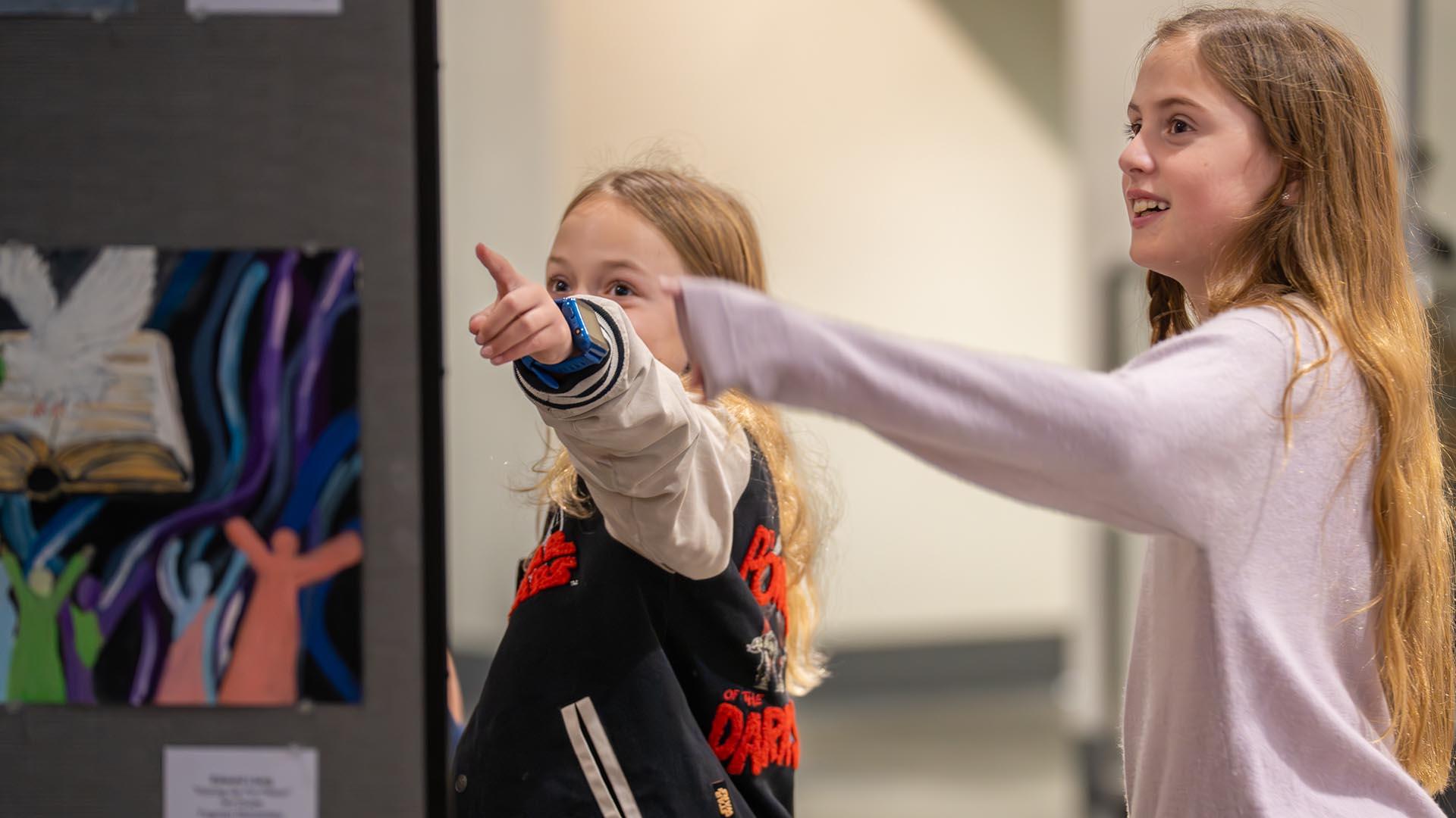 Two students point to the artwork in the lobby displays.