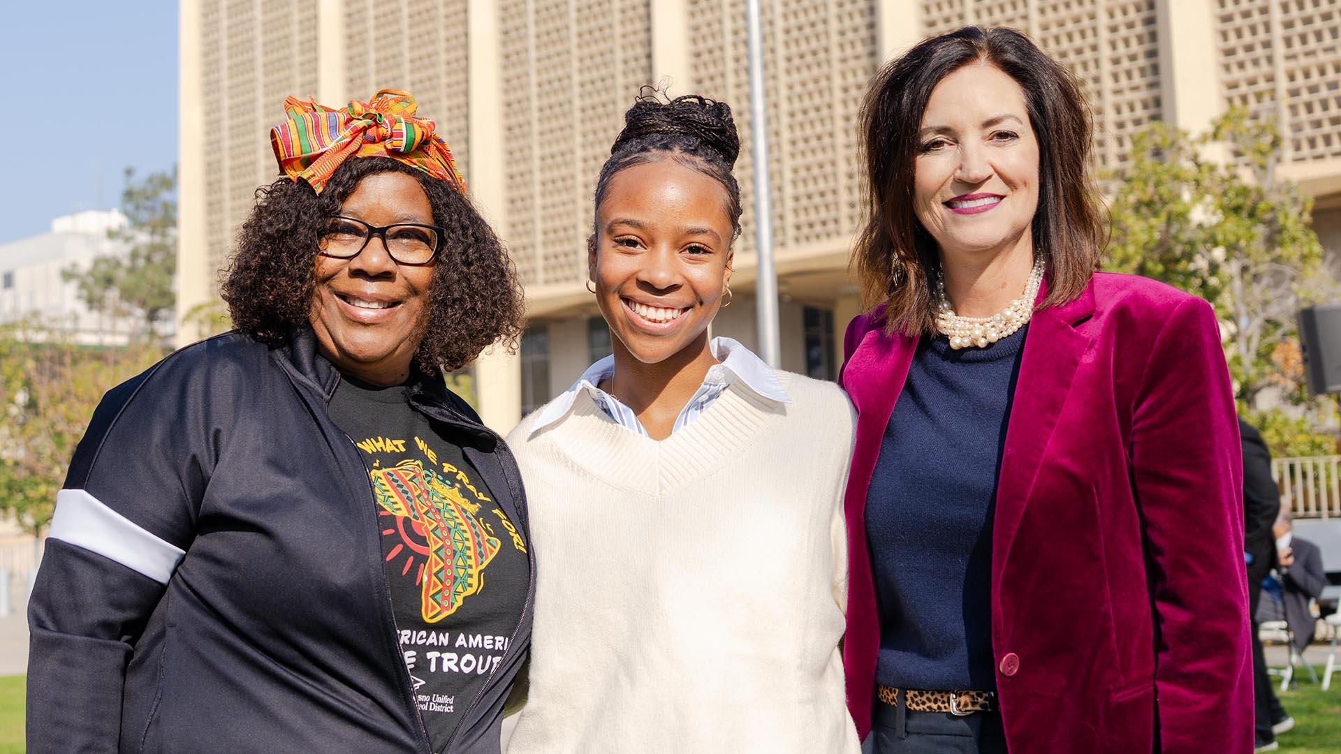 Three people are in line, smiling at the camera.