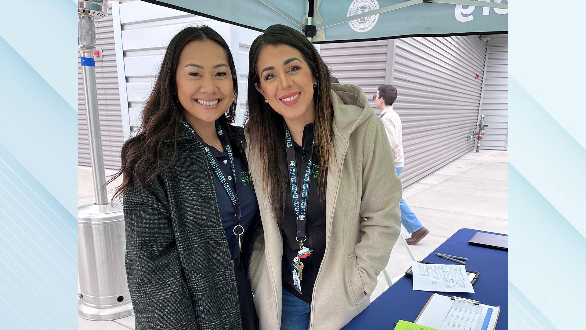 Two staff members at the check-in table are smiling