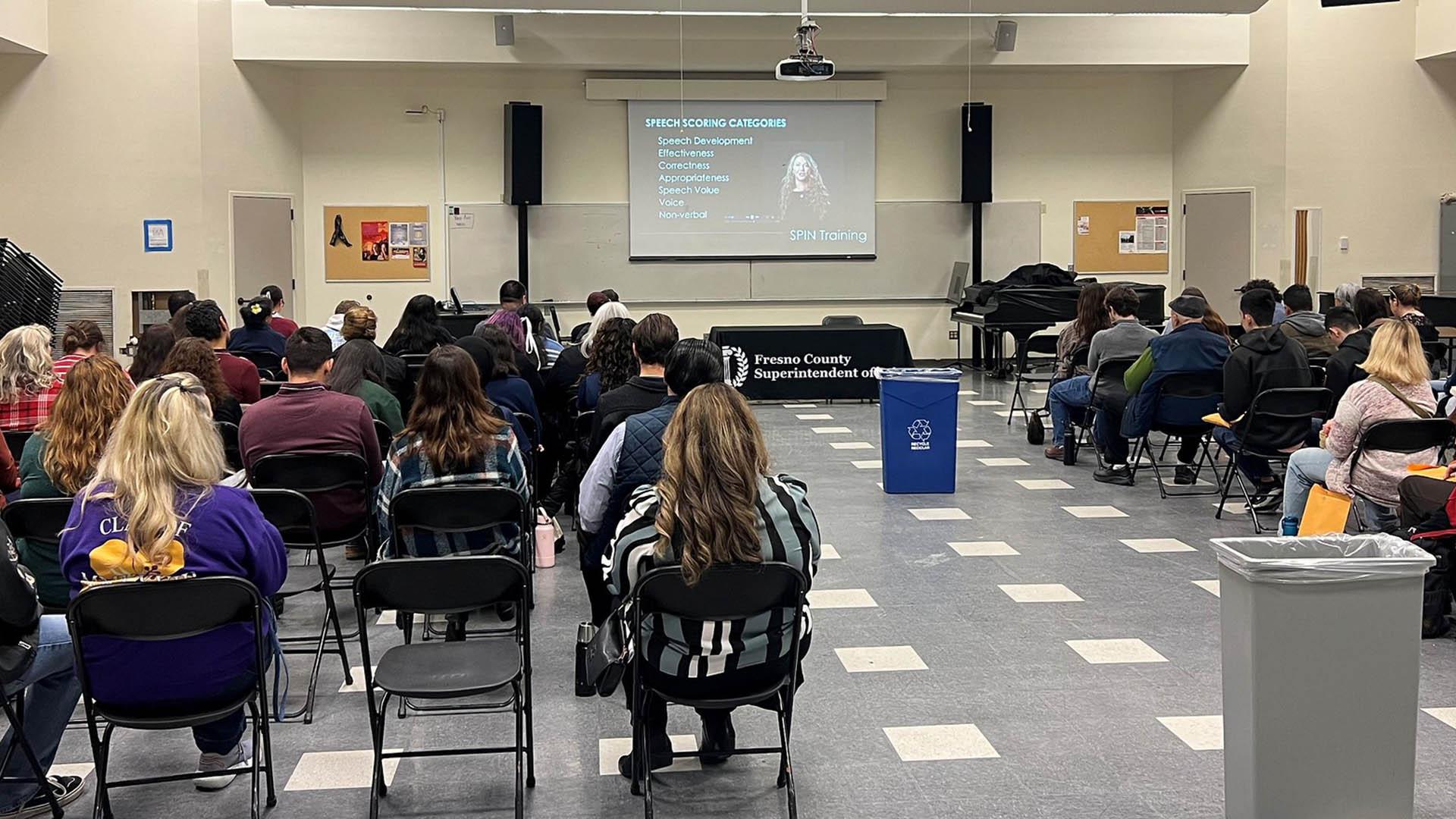 A picture is taken from the back of the room where they are recruiting judges.