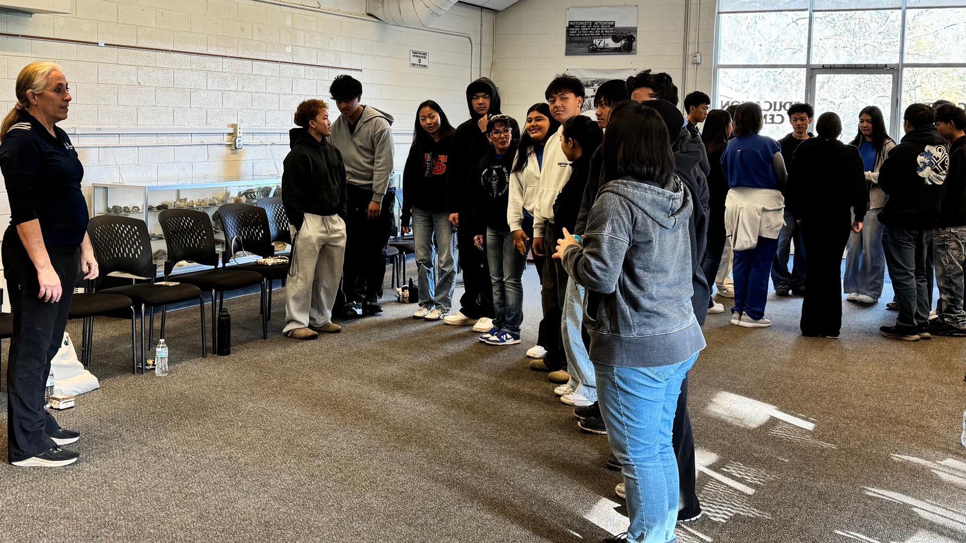 Students are in a classroom working on a ball-passing activity that teaches teamwork.