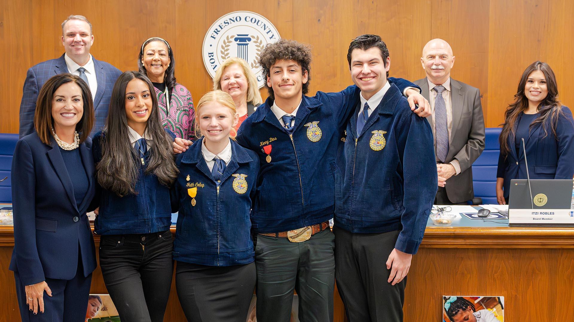 The honorees stand with the Superintendent and the Fresno County Board of Education, holding their plaques.