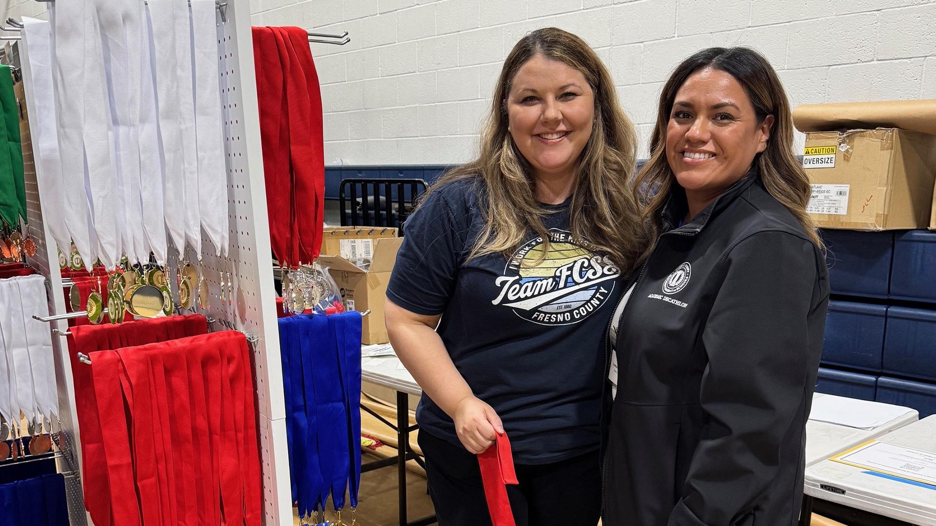 Two people are assisting with the award medals. 