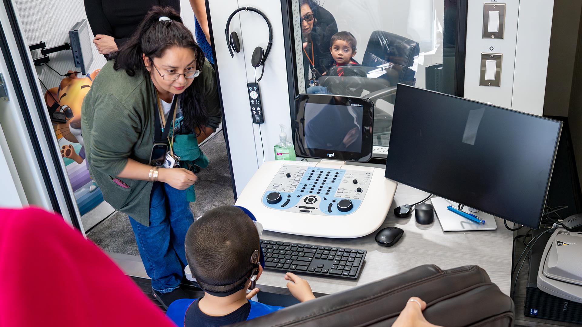 Children are trying out the sound booth with a staff member. 