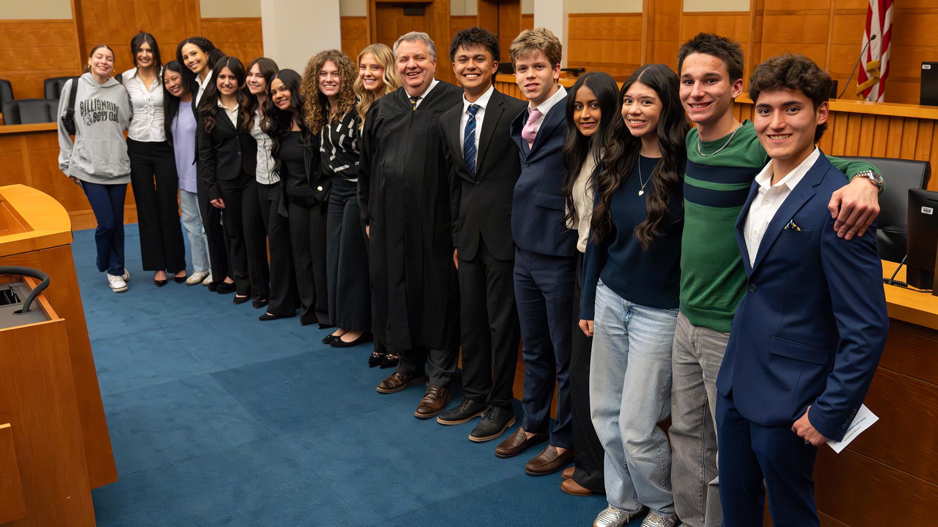 The team is standing together in the court room. 
