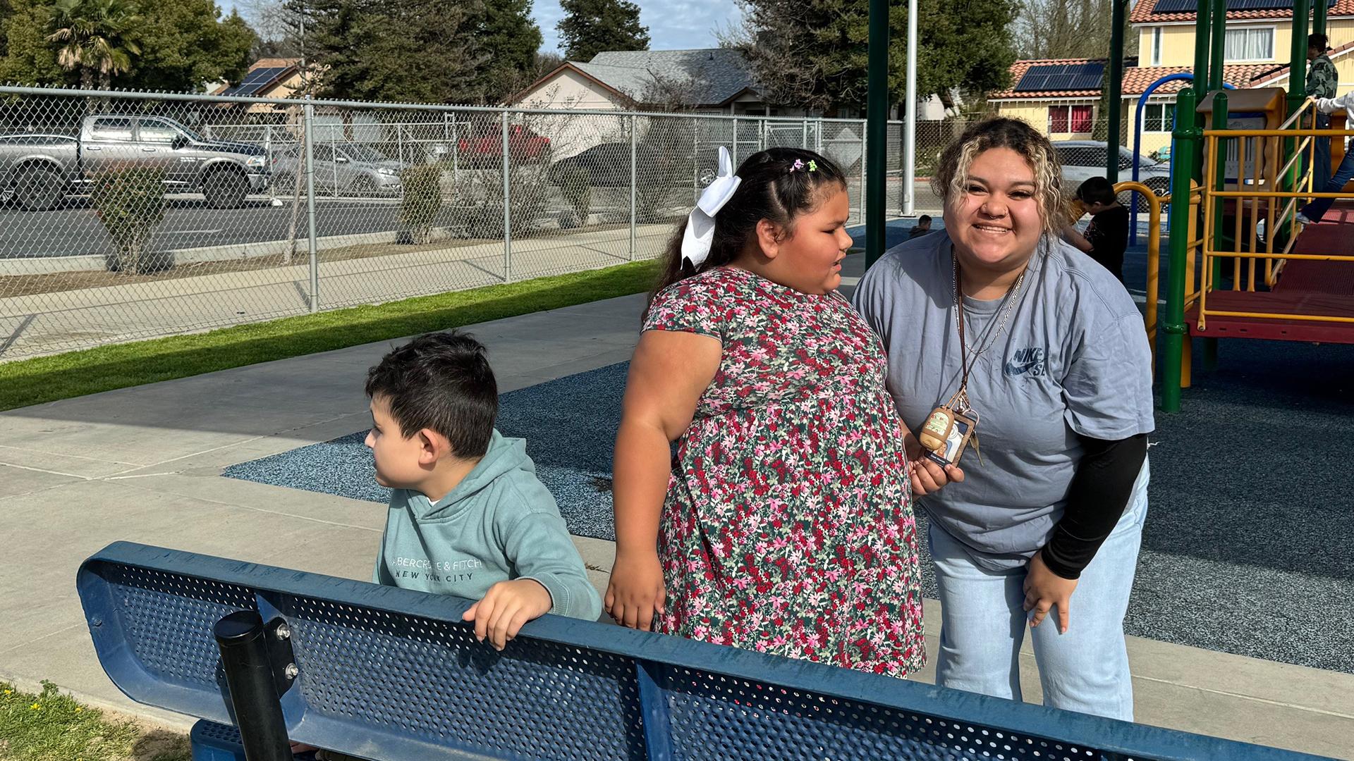 A teacher is with two students on the playground. 