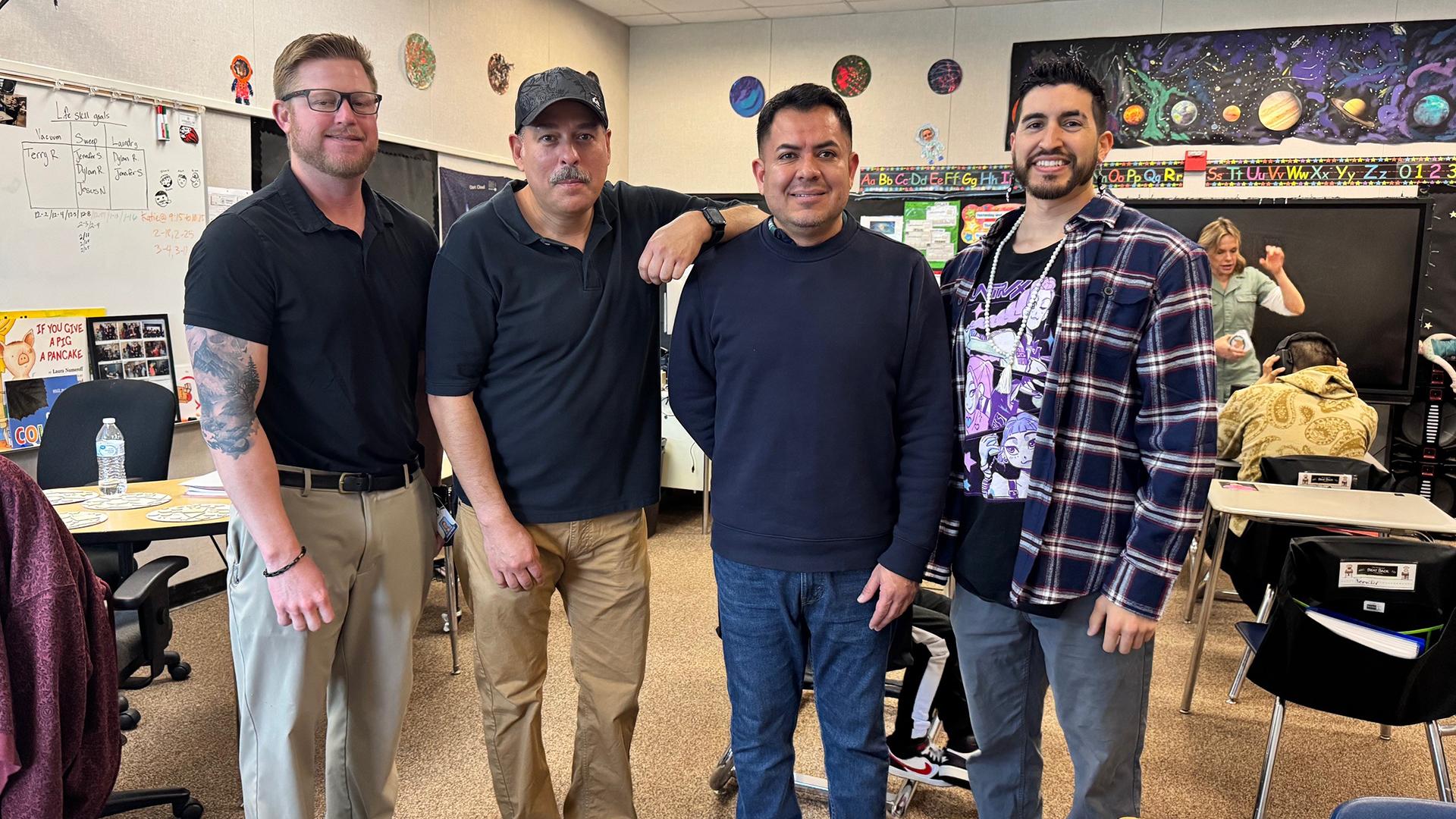 Four staff members are standing in a line, smiling. 