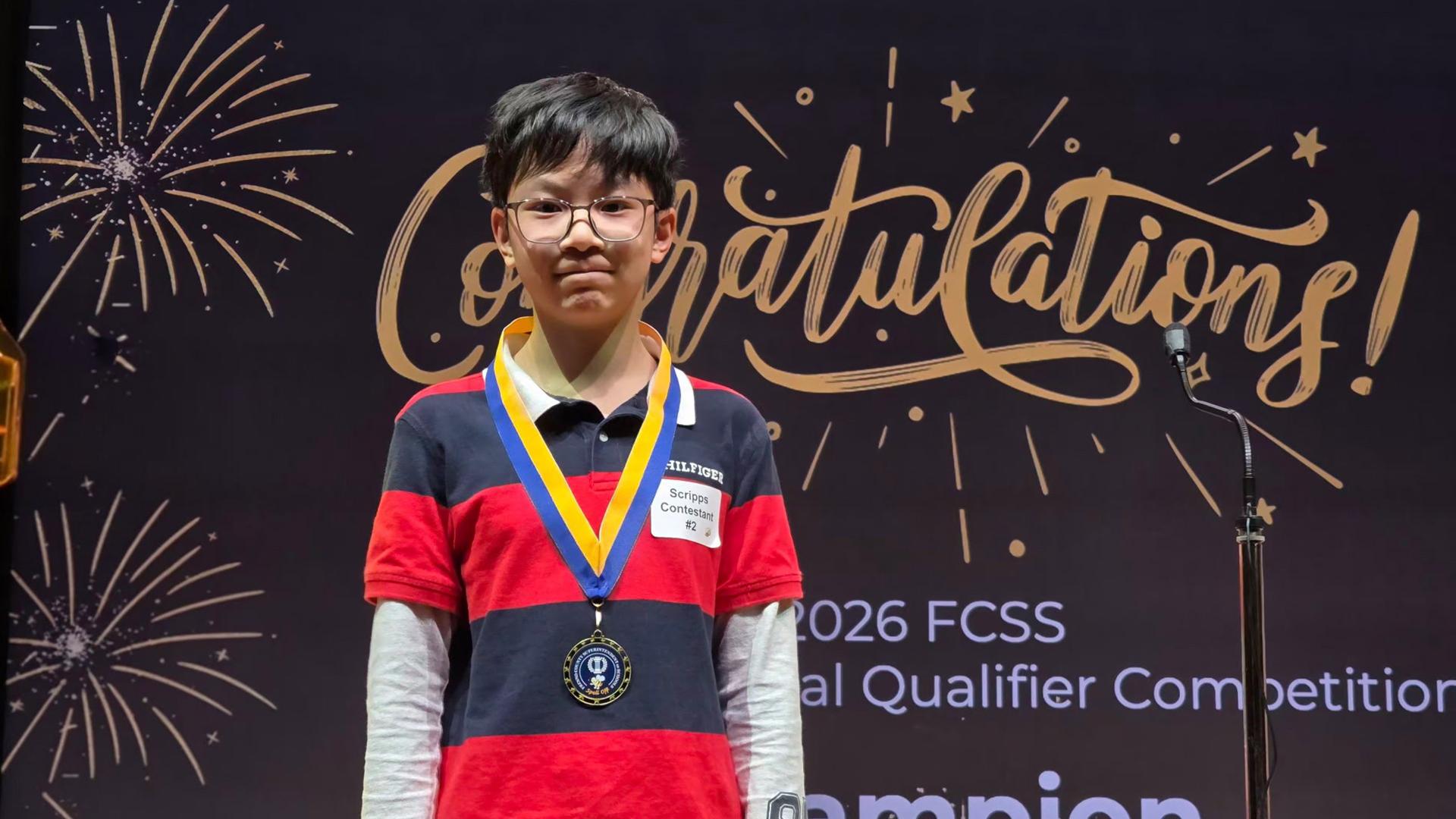 The winning student is standing with his medal. 