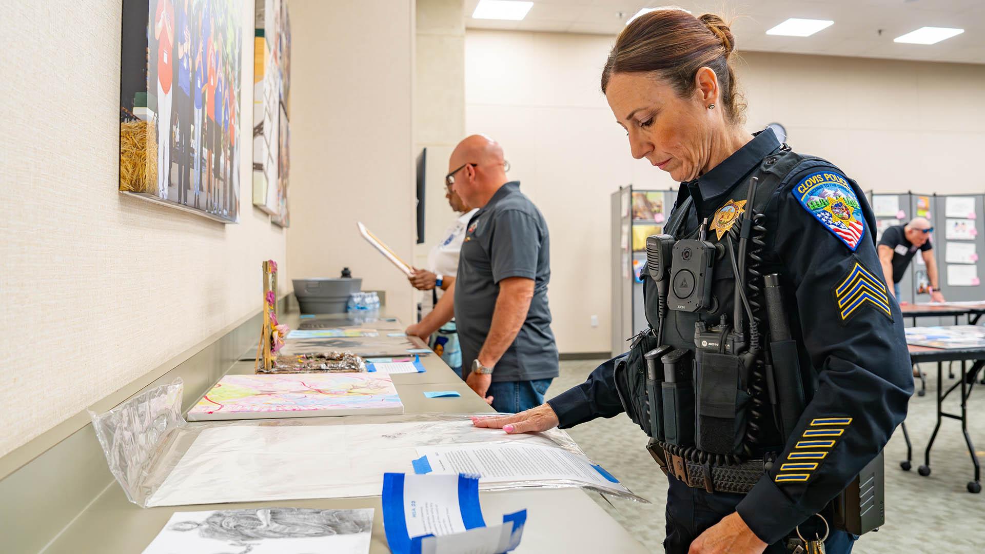 A person is judging student artwork. 
