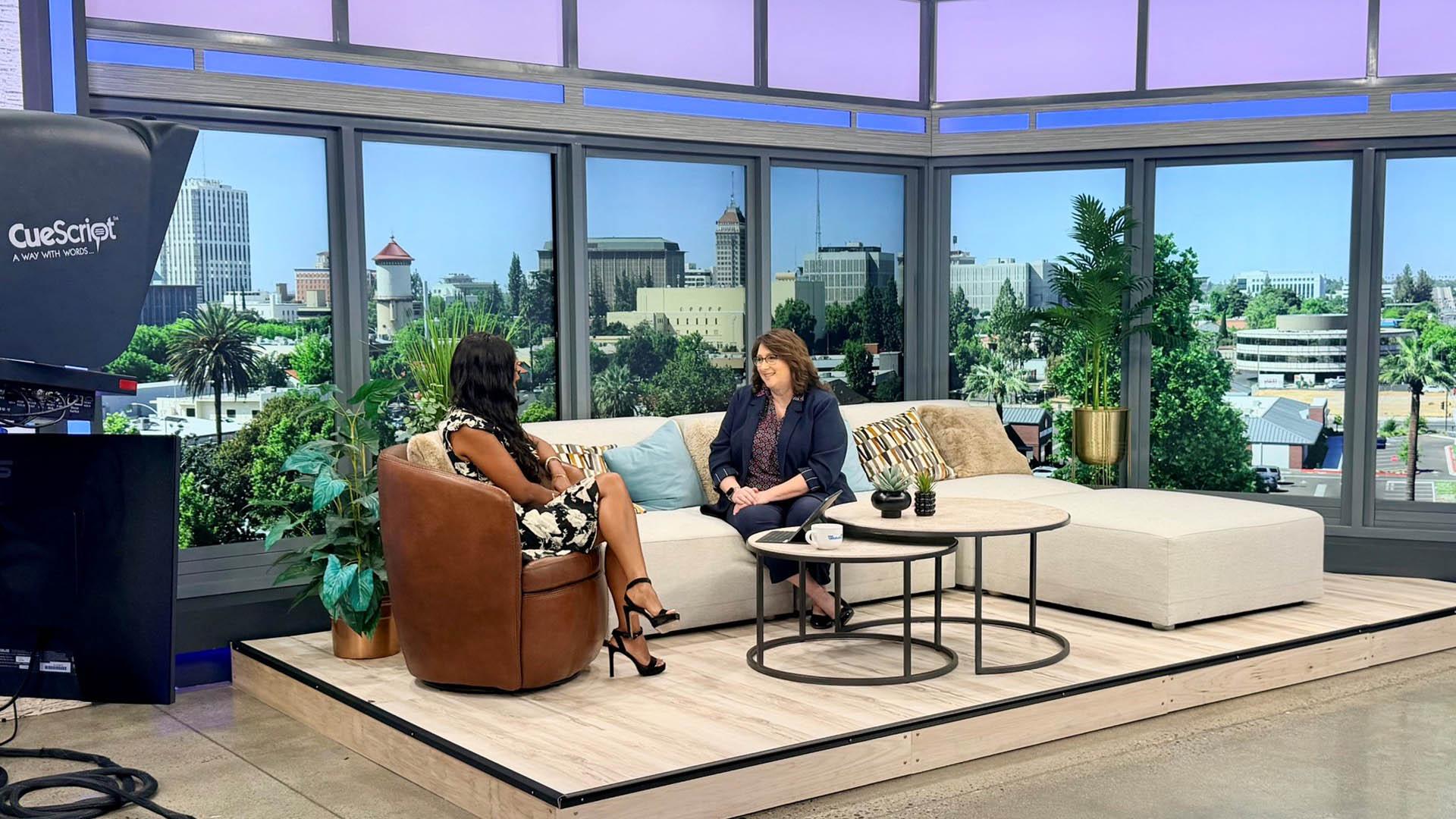 Two people sit on a couch while conducting an interview. 
