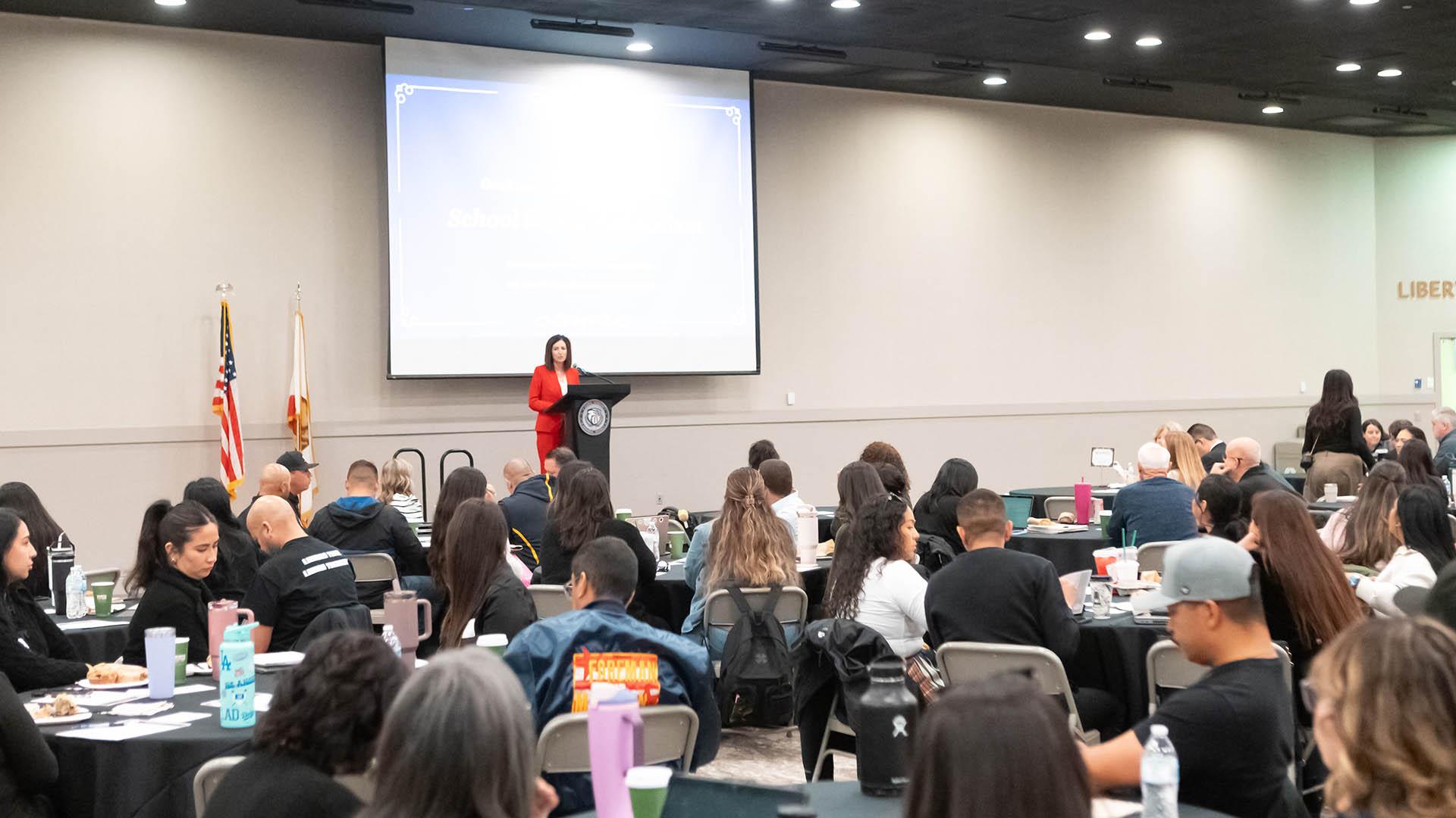 A room full of attendees listens to a speaker. 