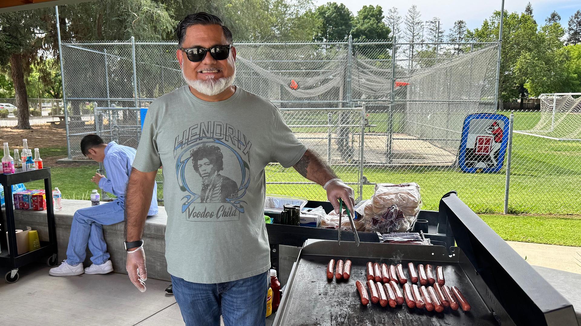 A teacher is grilling hot dogs. 