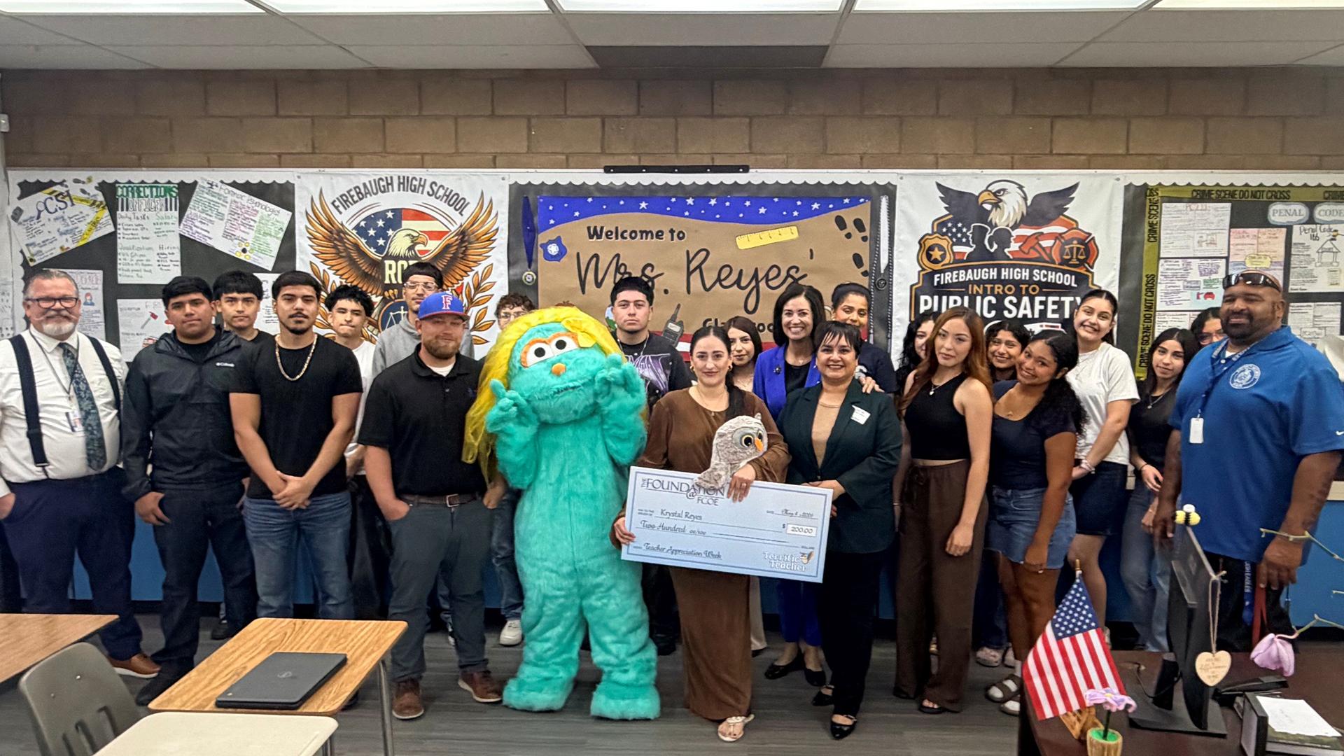 A teacher who received an award is standing with students. 