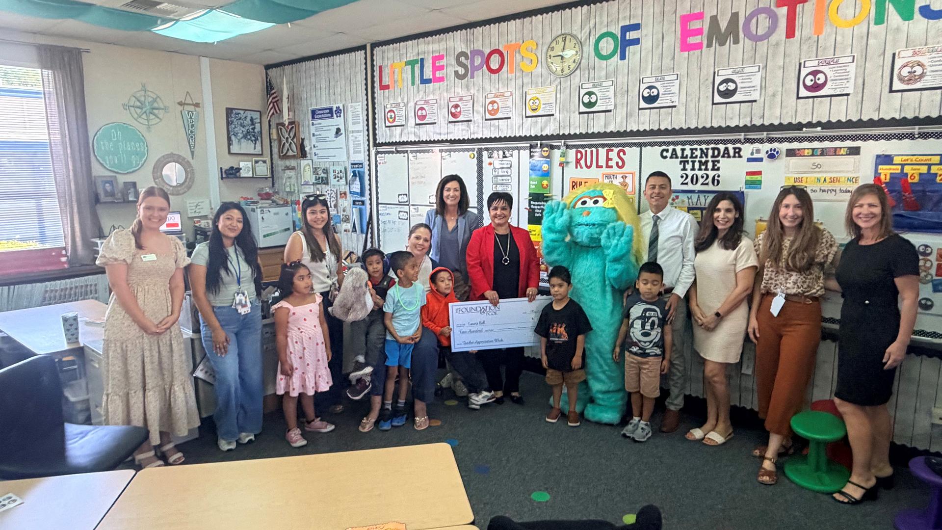 A teacher who received an award is standing with students. 