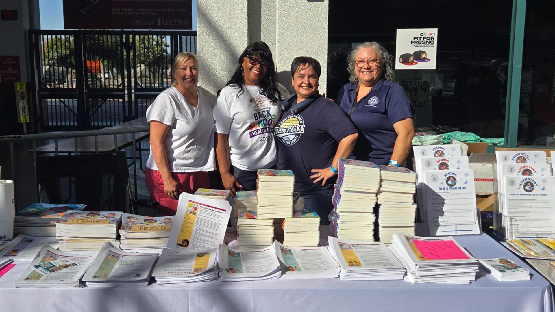 Four coworkers pose at a table outside the Health Fair.