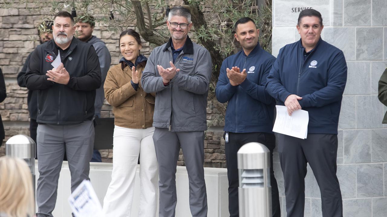 Team members smile and clap their hands during the ribbon-cutting.