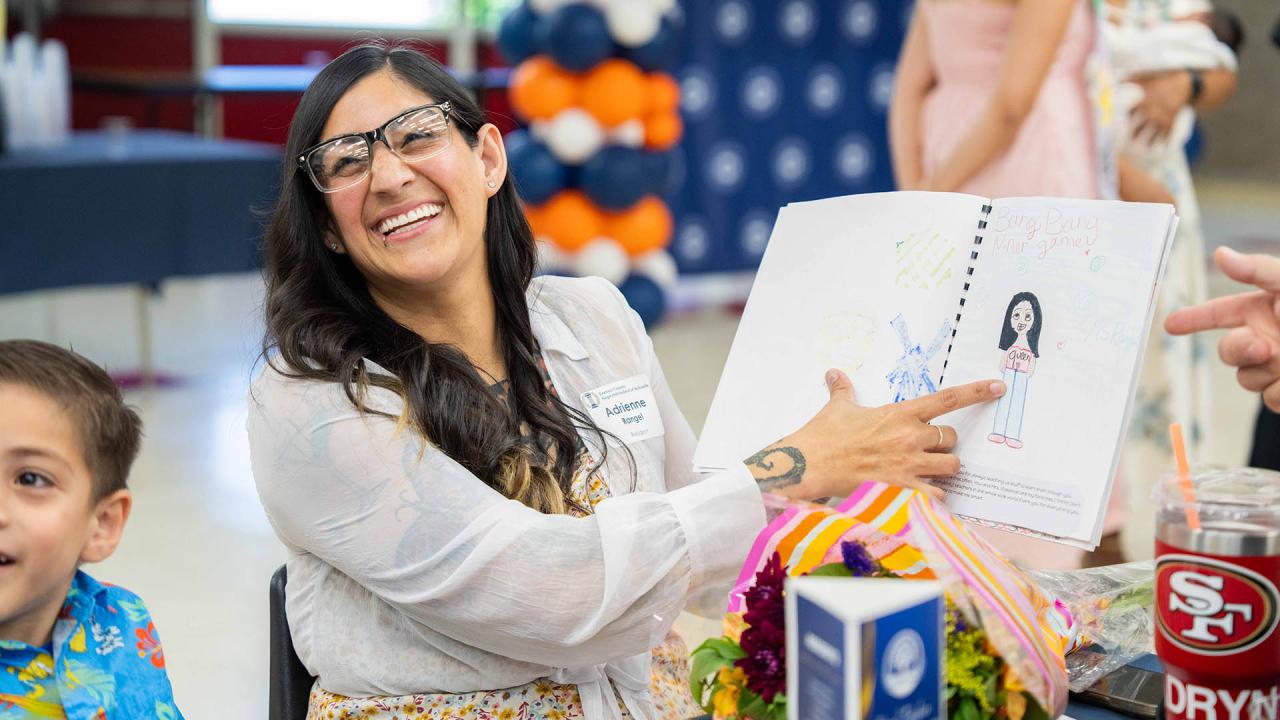 A participant holds up a drawing her child made for her. 
